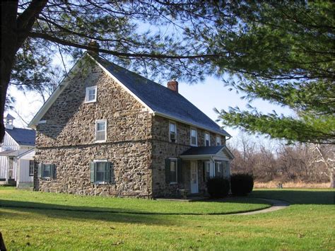 an old stone house sits in the middle of a grassy area next to a tree