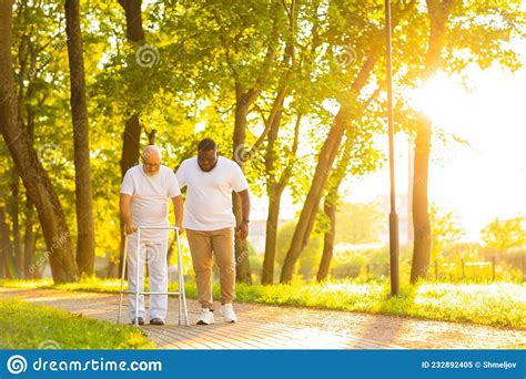 Caregiver Is Teaching Old Man To Walk With Walker Professional Nurse