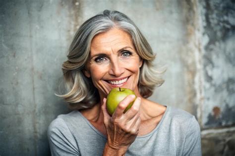 Portrait Of Happy Mature Woman Holding Granny Smith Apple At Home