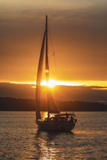 Foto vertical de um barco à vela no oceano durante o pôr do sol Foto