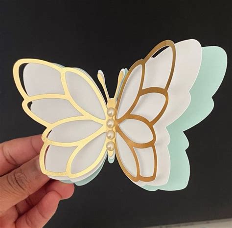 A Hand Holding A White And Gold Butterfly