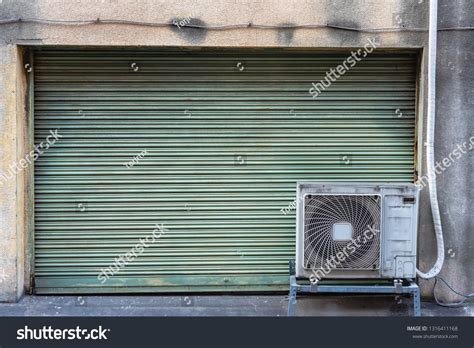 Grungy Weathered Metallic Roller Shutter Door With Old Air Conditioner