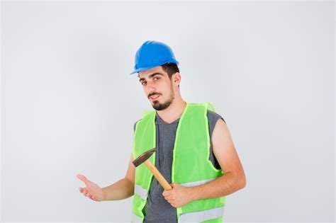 Jeune Homme En Uniforme De Construction Tenant Une Hache Et Tendant La