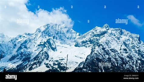 Wide panoramic view of snow covered mountain peak and blue sky with ...