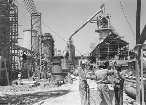 An Old Black And White Photo Of Men Working In A Factory With Large