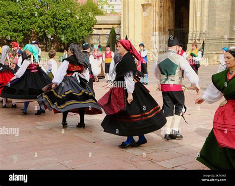 A folk dance group in traditional costumes dancing to bagpipe music in front of Oviedo cathedral ...