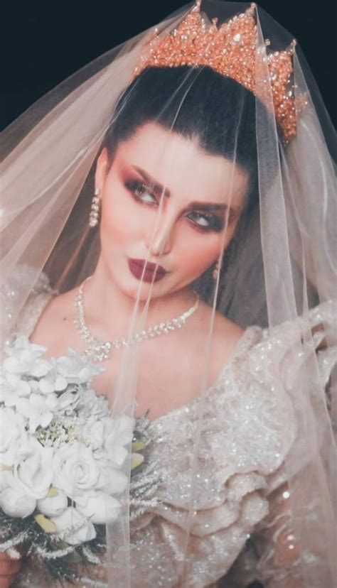 A Woman Wearing A Tiara And Holding A Bridal Bouquet In Front Of Her Face