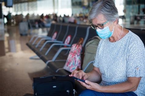 Premium Photo Senior Female Traveler Sitting In Airport With Luggages