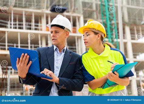 Man Engineer Standing On A Construction Site With A Young Woman Worker