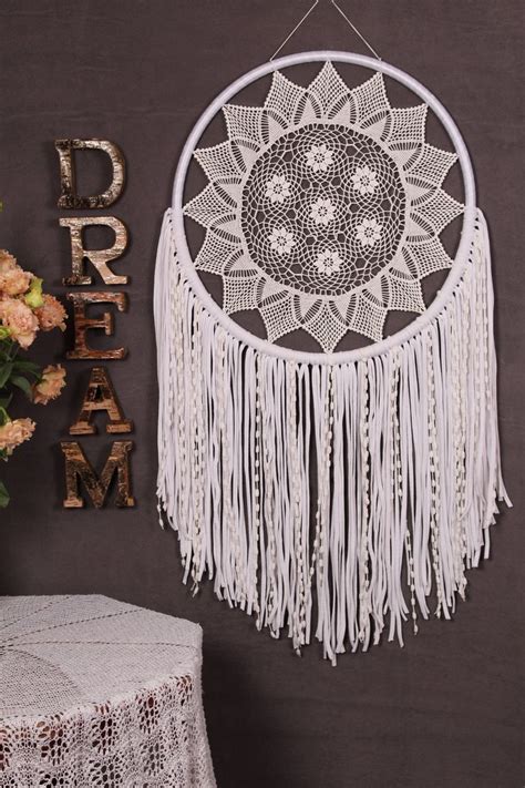 A White Doily Hanging From The Side Of A Wall Next To A Vase With Flowers