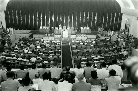 An Assembly Room Full Of People Sitting And Standing In Front Of A