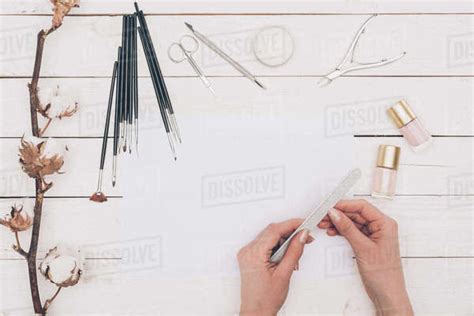 Cropped image of woman filing nails with nail file - Stock Photo - Dissolve