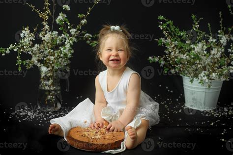 Little girl celebrates her first birthday. Girl eating her first cake