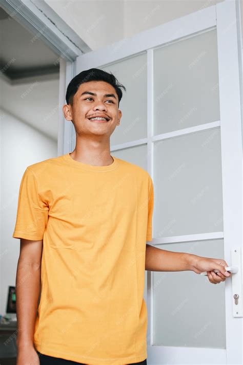 Premium Photo | Happy young Asian man open his front house door and smiling