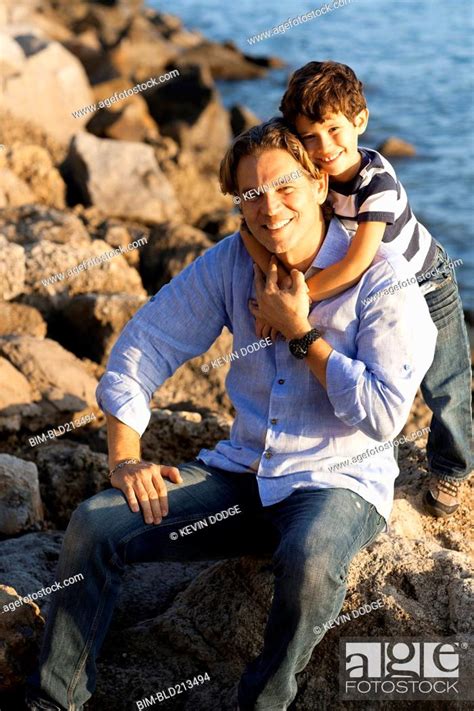 Caucasian Father And Son Hugging On Rocky Beach Stock Photo Picture