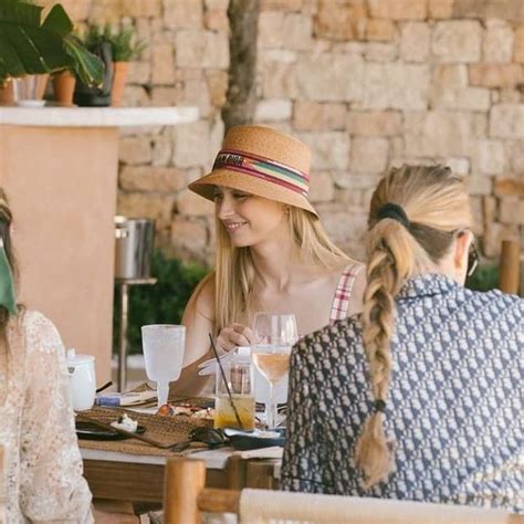 Three Women Sitting At A Table With Drinks In Their Hands And One Woman