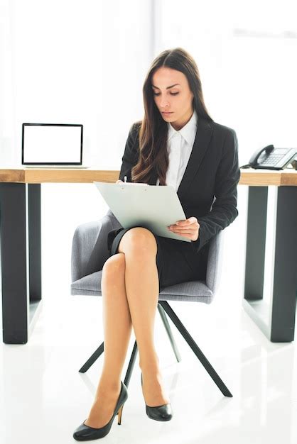 Jeune Femme Assise Sur Une Chaise Avec Les Jambes Croisées écrit Sur