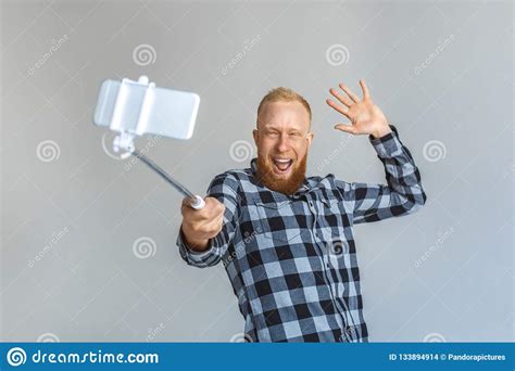 Freestyle Mature Man Standing Isolated On Grey With Monopod Taking