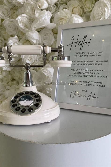 An Old Fashioned Phone Sitting On Top Of A Table Next To A White Flower