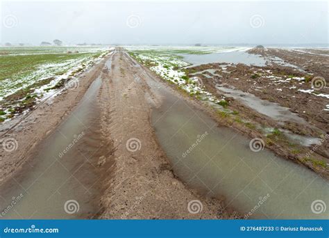 Puddles On Dirt Road Through Fields With Snow Water And Mud Stock