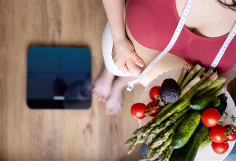 Mujer con sobrepeso en la cocina con centímetro de cinta métrica en la