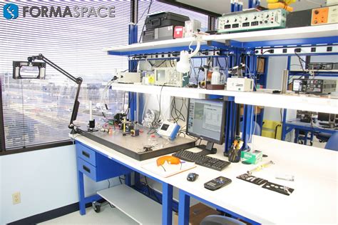 A Desk With A Computer On Top Of It In A Room Filled With Shelves And