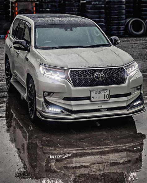 The Front End Of A Silver Suv Parked In A Parking Lot On A Rainy Day