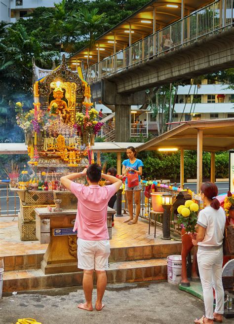 People worshipping Phra Phrom, the four faced Brahma, in the roadside Thai Buddhist temple ...