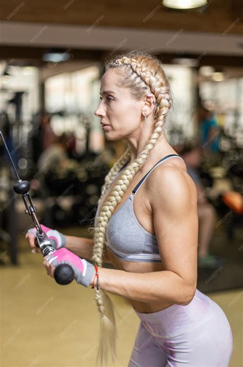 Una joven atlética entrena los músculos de los brazos en una máquina de