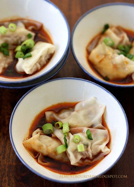 Three White Bowls Filled With Dumplings On Top Of A Wooden Table