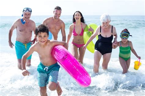 Família de várias gerações correndo na praia Foto Premium