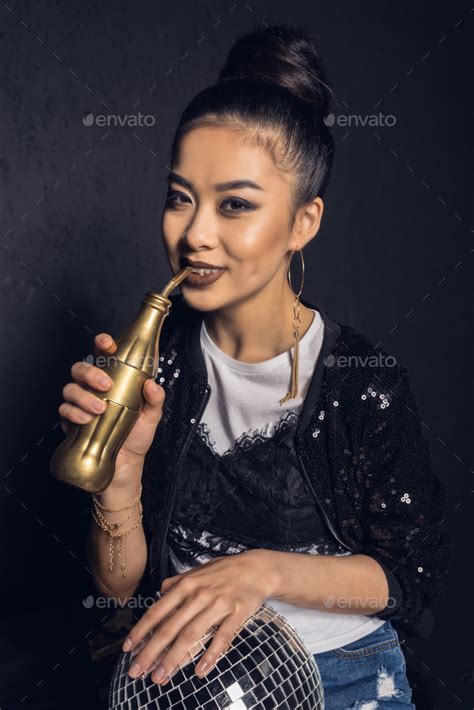 Glamour Asian Disco Girl With Golden Bottle And Disco Ball Smiling And