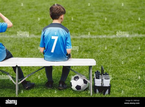 Schoolboy sitting on soccer bench. Young boy sitting on the substitute bench. Football sports ...