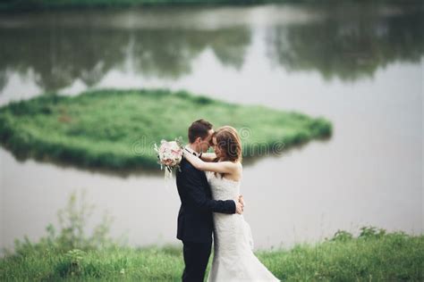 Beautifull Wedding Couple Kissing And Embracing Near Lake With Island