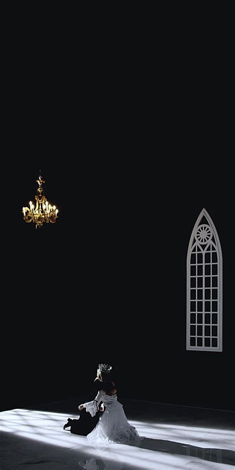 A Bride And Groom Sitting On The Floor In Front Of A Chandelier At Night