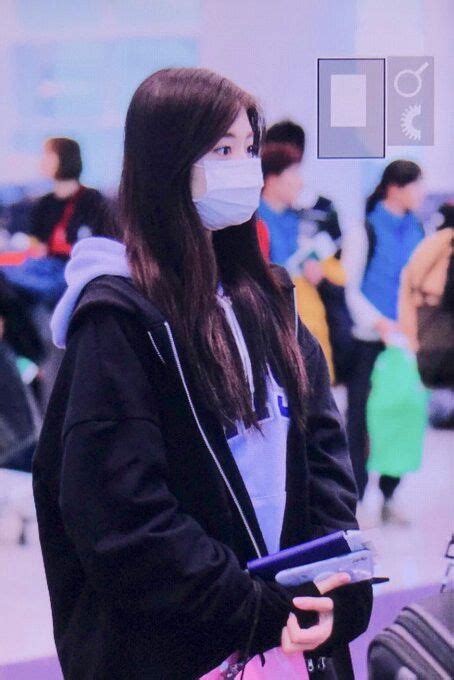 A Woman Wearing A Face Mask And Holding A Pink Bag In An Airport