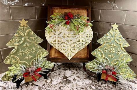 Three Small Christmas Trees Are On Display In Front Of A Brick Wall