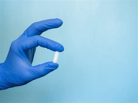 La vela rectal se sostiene con una mano en un guante médico azul