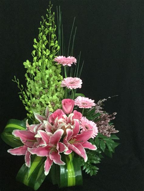 A Vase Filled With Pink And Green Flowers On Top Of A Black Table Next