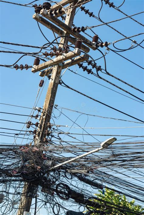 A Jumble Of Electrical And Telephone Wires Attached To A Utility Pole