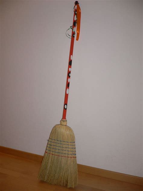 A Broom Sitting On Top Of A Hard Wood Floor Next To A White Wall With