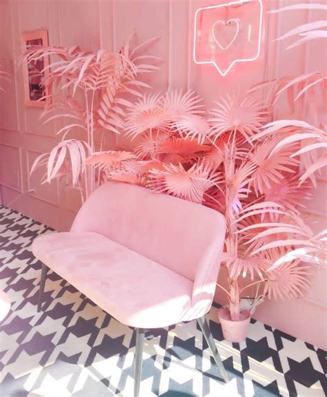 a pink chair sitting next to a palm tree on top of a black and white ...