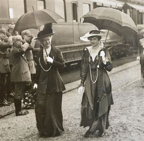 Two Women Walking Down The Train Tracks With Umbrellas Over Their Heads