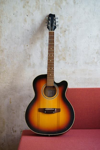 Guitarra acústica vintage negra y naranja en el sofá rojo en un