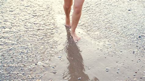 Tanned Female Legs On Beach Water Splashing On Feet In Ocean On Sandy