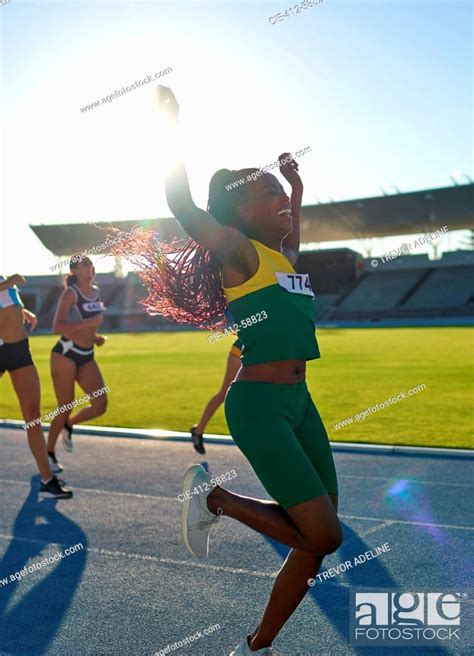 Happy Female Track And Field Athlete Winning Race On Sunny Track Stock