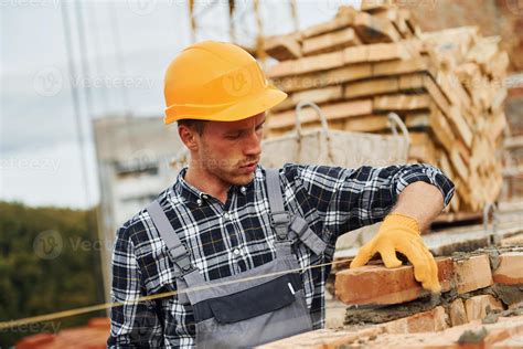 Pose De Briques Ouvrier Du Bâtiment En Uniforme Et équipement De