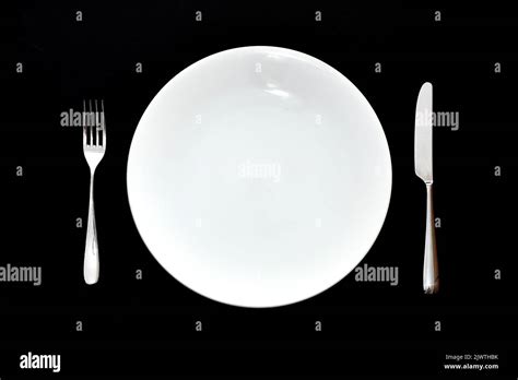 Stainless Steel Knife And Fork And Empty White Dinner Plate On A Plain