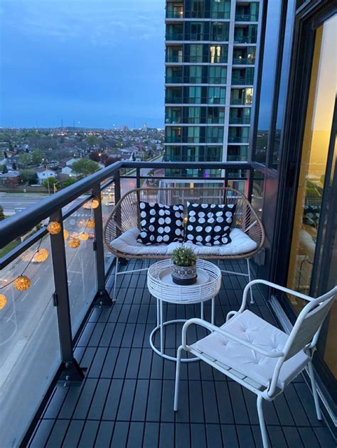 A Balcony With Two Chairs And A Table On Top Of It Overlooking The City