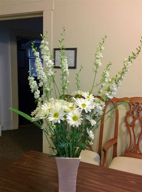 A Vase Filled With White Flowers Sitting On Top Of A Table Next To A